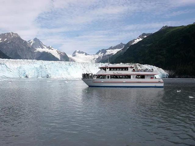 A tour boat floating in icy water near a large glacier.